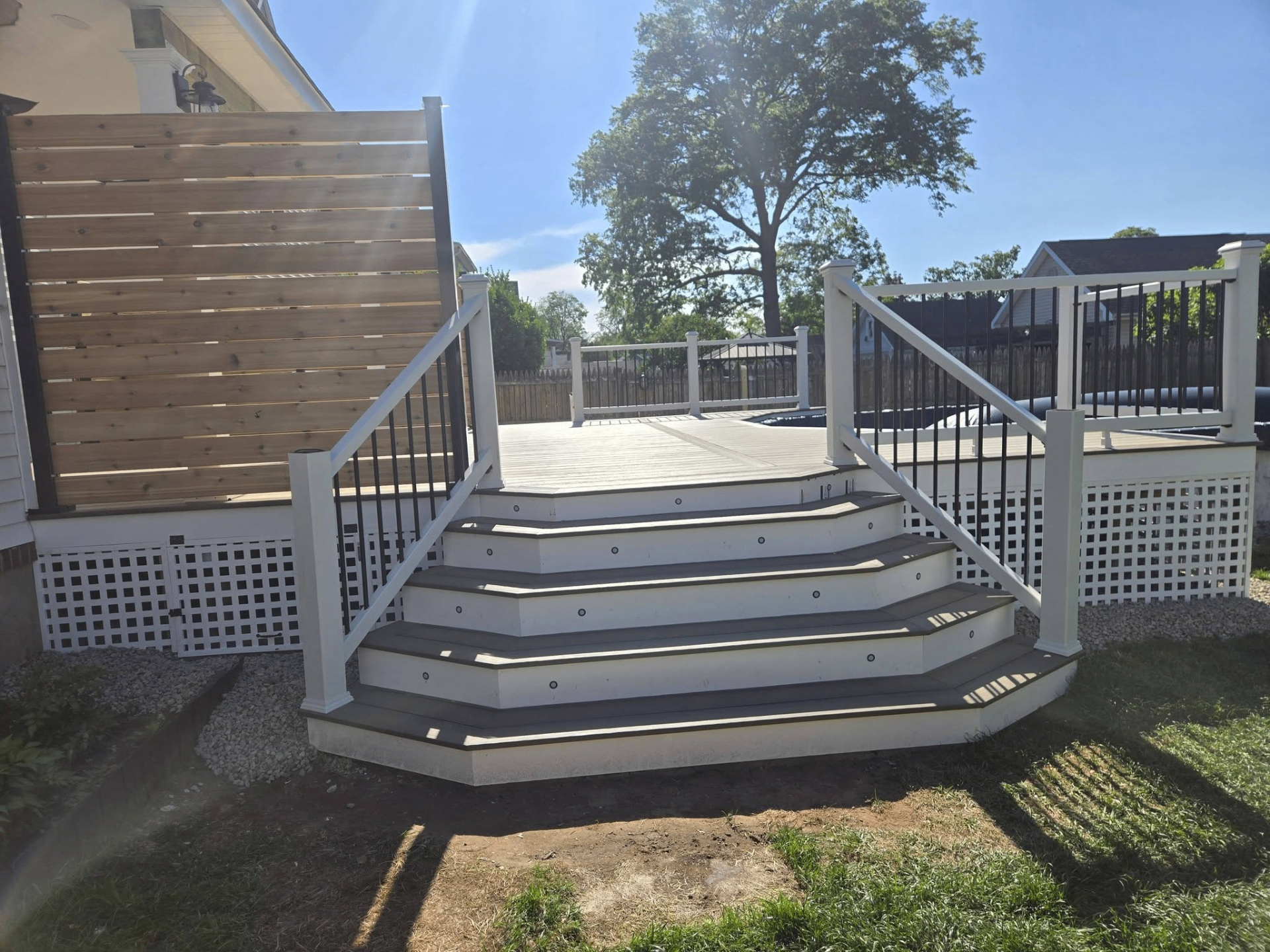Custom deck with white railings, hexagonal stairs and lattice skirting in Union County NJ